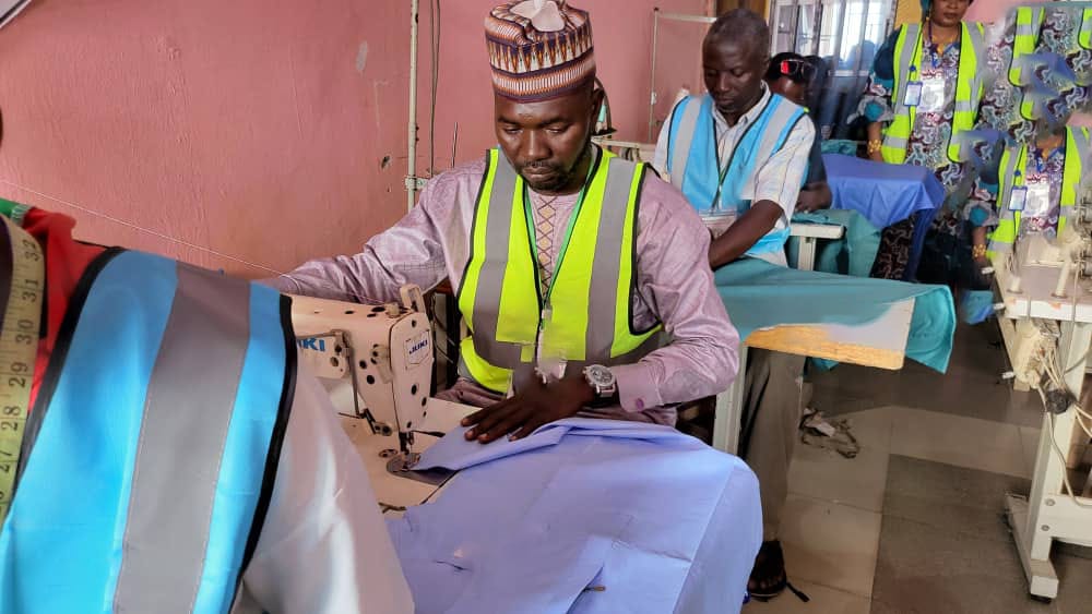 Trainee in yellow vest working at sewing machine during the seminar