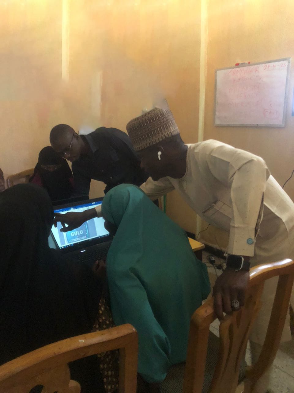 Trainer closely assisting participant on laptop during ICT class